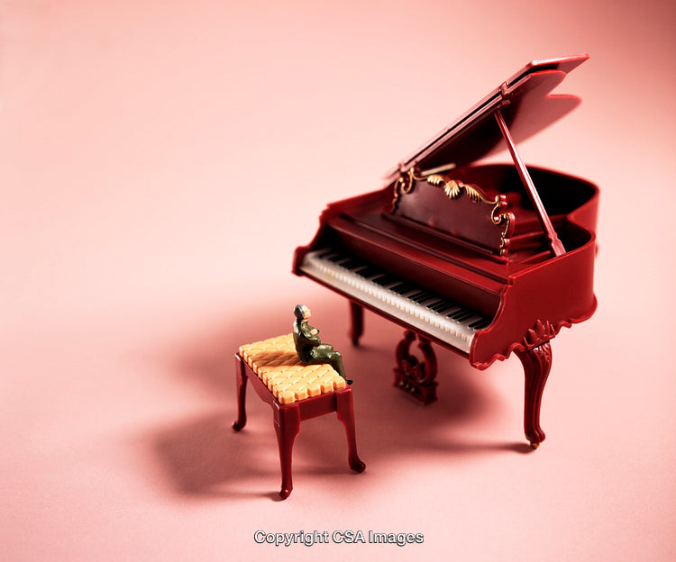Miniature Model of a Red Grand Piano with Bench on Pink Background