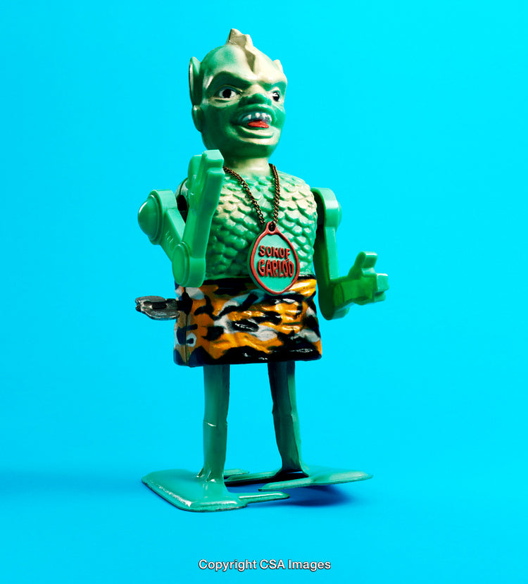 Vintage Green Monster Toy With Wind-Up Mechanism on Blue Background