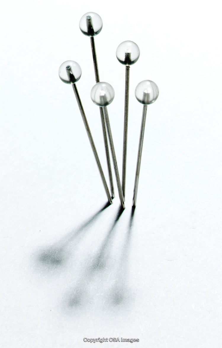 Close-Up of Metallic Pins on a White Reflective Surface