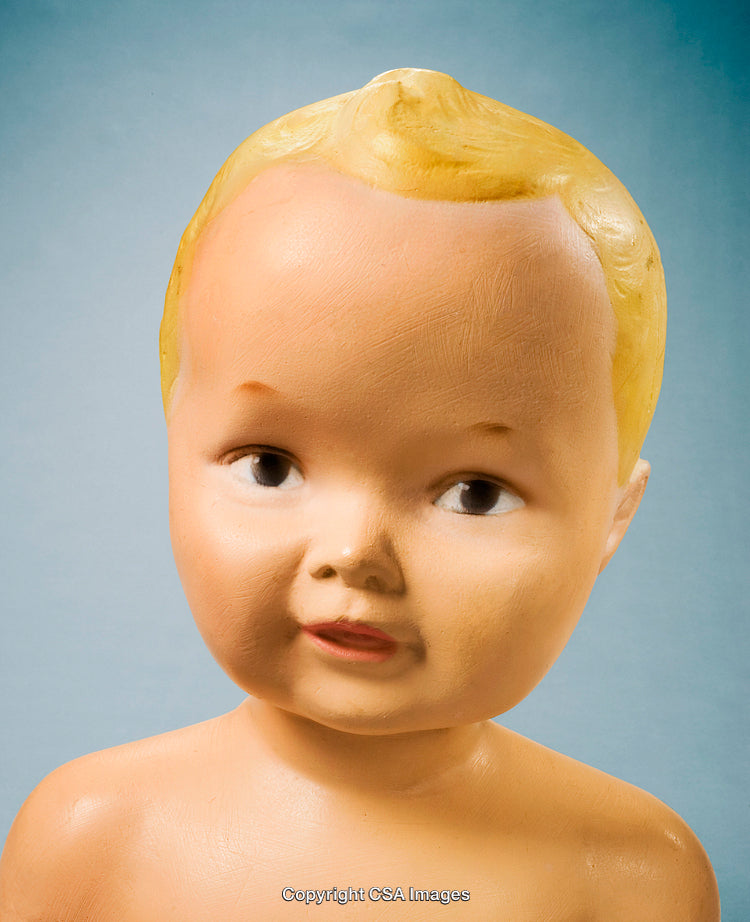 Closeup Photograph of a Vintage Plastic Doll Against a Blue Background