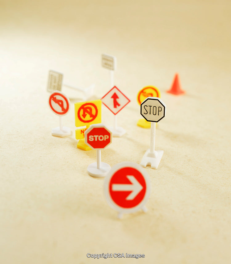 Collection of Miniature Plastic Road Signs on a Neutral Background