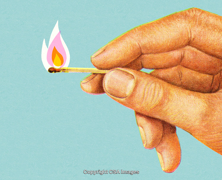 Hand Holding a Lit Matchstick Against a Blue Background