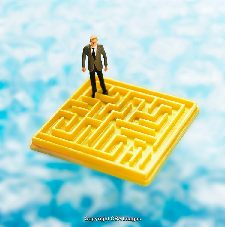 Miniature Businessman Figurine Standing on a Yellow Plastic Puzzle Maze