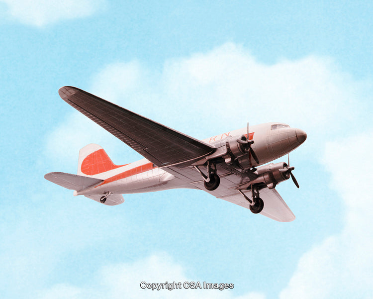 Vintage Airplane Toy Flying Against a Blue Sky With Clouds
