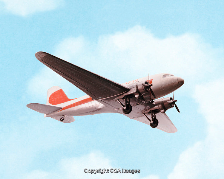 Vintage Airplane Toy Flying Against a Blue Sky With Clouds