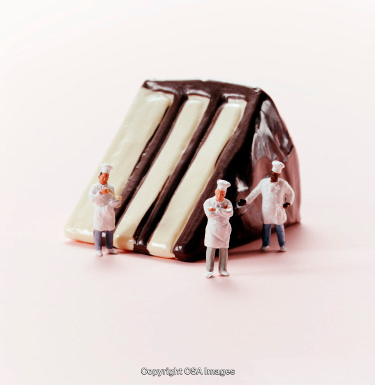 Miniature Chefs Working Beside a Large Chocolate Cake Slice