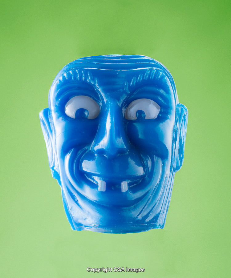 Blue Plastic Face Toy Against Vibrant Green Background