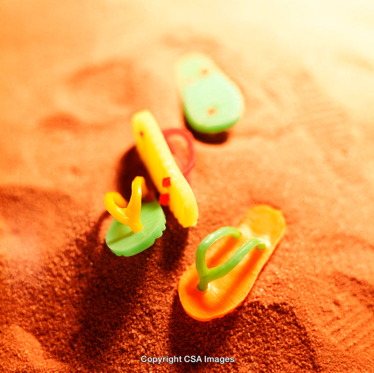 Colorful Plastic Sandals Scattered on Sunlit Sandy Beach