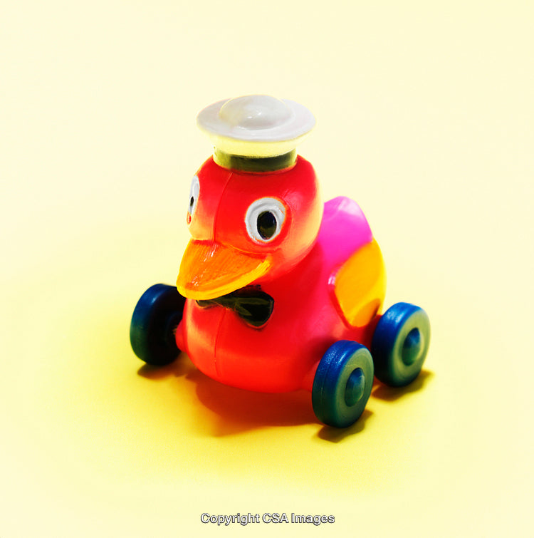 Colorful Plastic Duck Toy with Wheels on Yellow Background