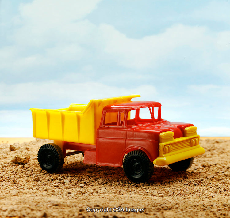 Colorful Plastic Dump Truck Toy on Sandy Surface With Blue Sky Background