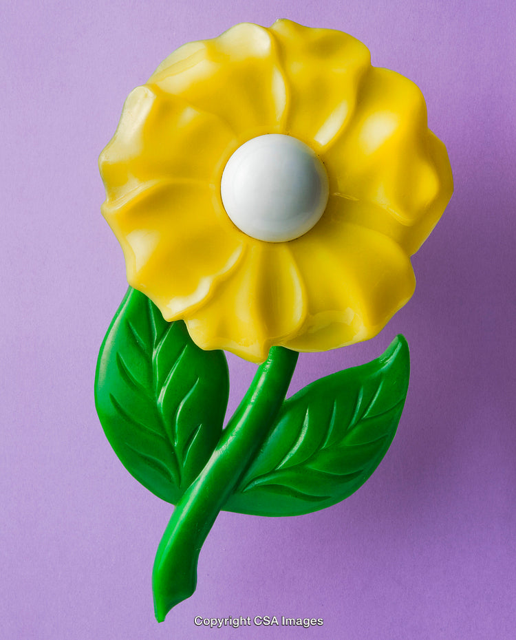 Yellow Flower-Shaped Plastic Toy on a Light Purple Background