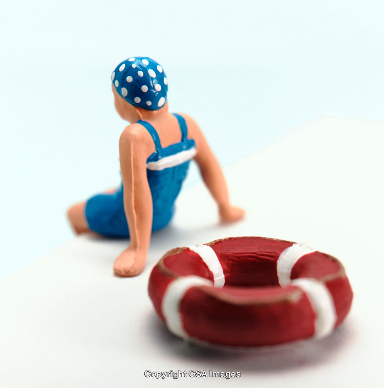 Toy Swimmer Figure and Red Lifebuoy on White Surface