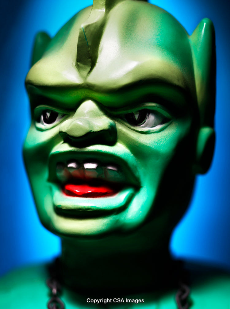 Close-Up of a Green Figurine with Expressive Features and Blue Background