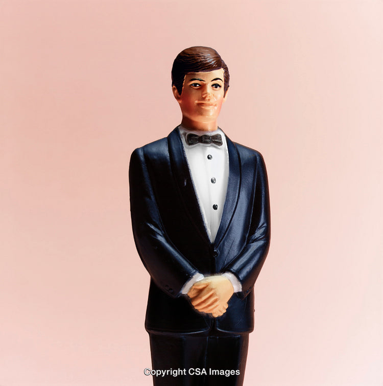Plastic Model of a Groom in a Formal Tuxedo on Pastel Pink Background