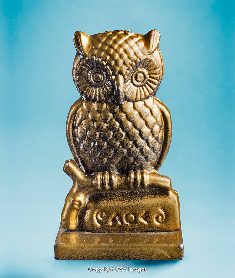 Golden Owl Figurine on Branch Against Blue Background