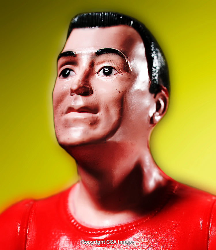 Close-Up of a Red-Clothed Plastic Figurine on Yellow Background