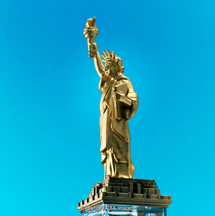Golden Statue Of Liberty Figurine against Vibrant Blue Background