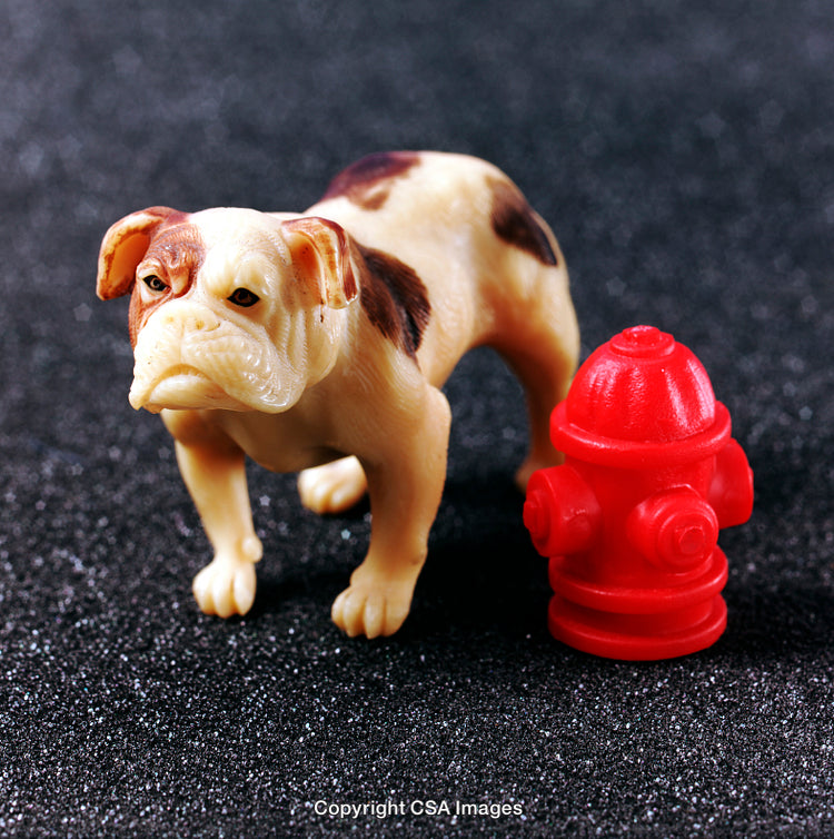 Plastic Bulldog Figurine Next to Red Fire Hydrant on Dark Background