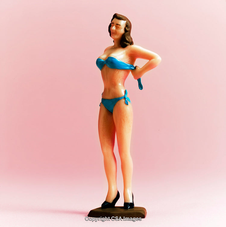 Retro Plastic Figurine of Woman in Blue Swimsuit Against Pink Background