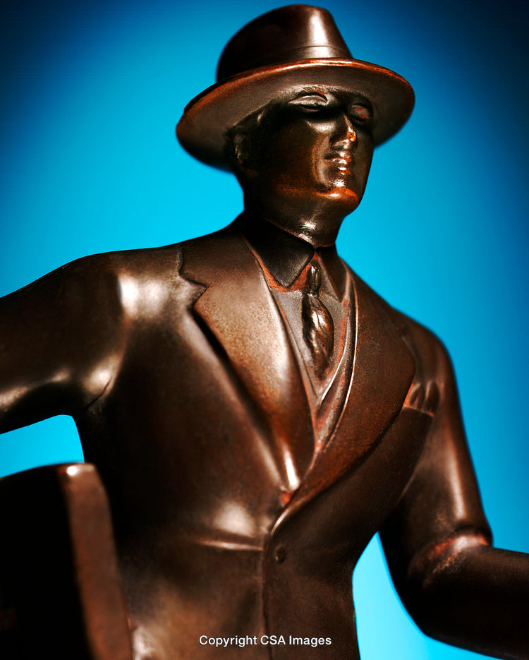 Close-Up of Suit-Wearing Bronze Figurine Against Blue Background