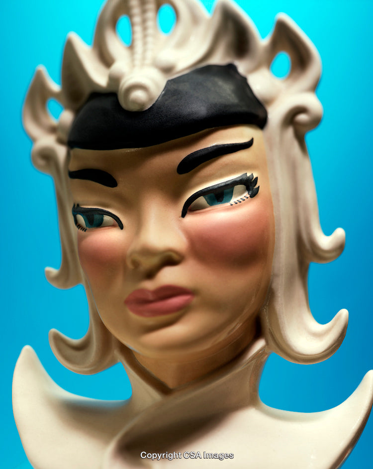 Closeup of an Ornate Ceramic Figurine Against a Blue Background