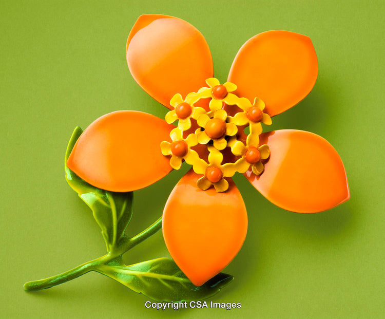 Colorful Plastic Orange Flower With Green Leaves on Green Background