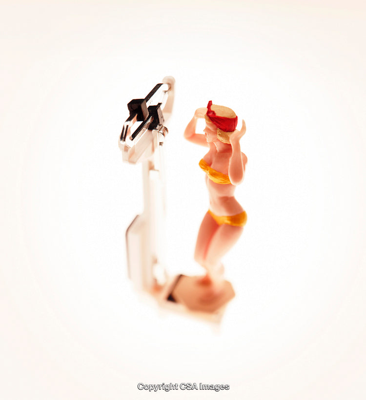Plastic Toy Figure of Woman Standing on Scale in Bright Light
