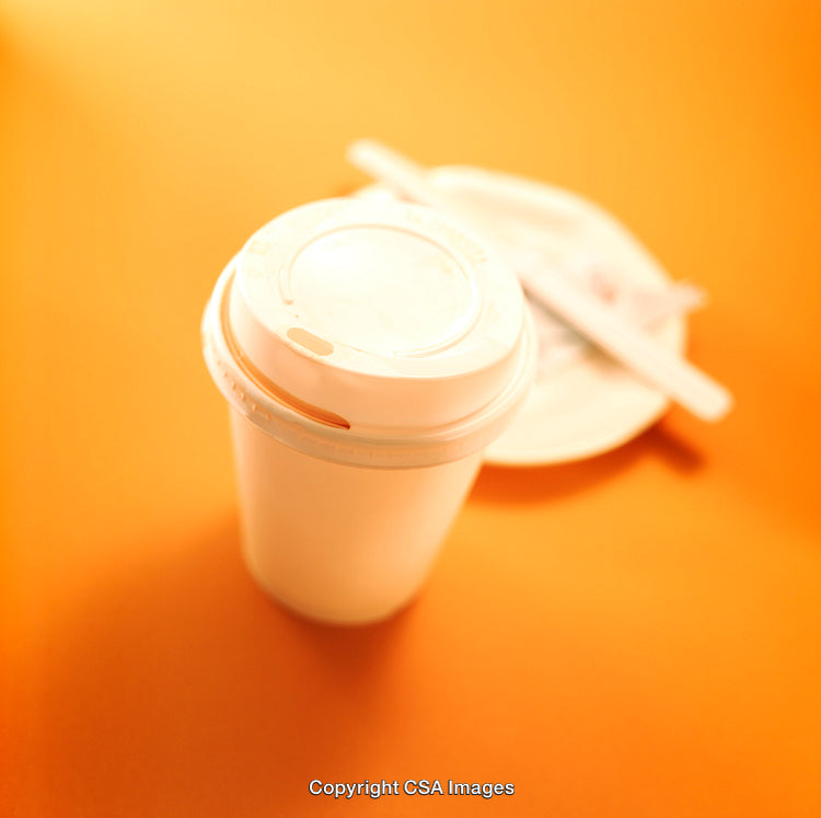 Coffee Cup with Lid on Bright Orange Background Illuminated by Warm Light