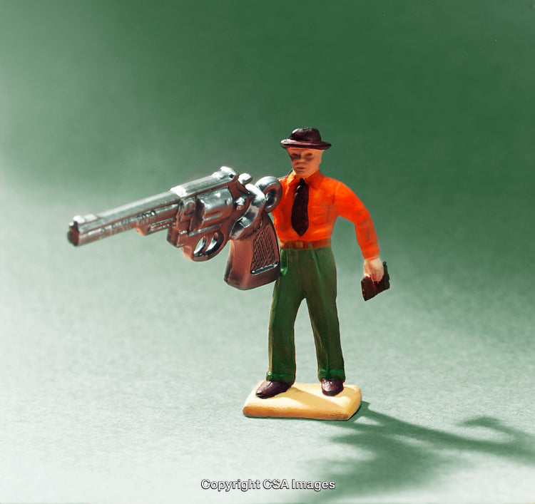 Colorful Plastic Figure Holding Oversized Silver Gun in Dramatic Lighting