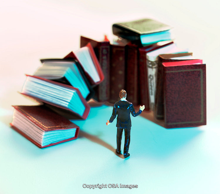 Miniature Figurine Standing Near a Stack of Oversized Books